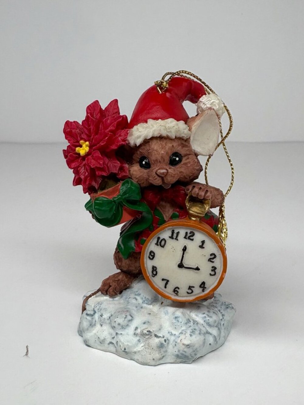festive resin mouse figurine holding an orange clock and a red poinsettia orname